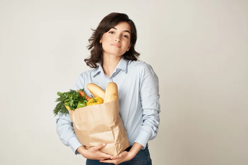 Женщина с пакетом продуктов, домохозяйка, совершающая покупки в супермаркете