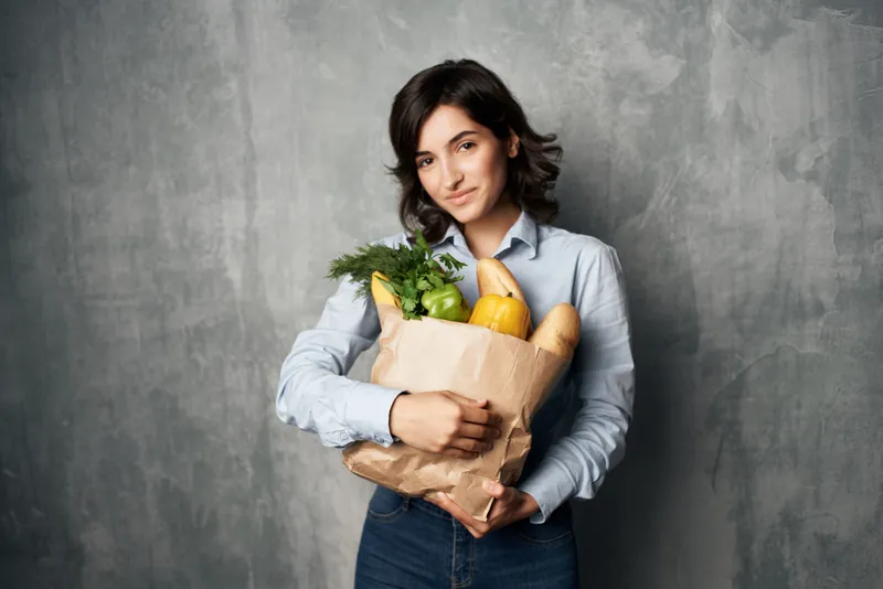Брюнетка с пакетом продуктов из супермаркета, овощи, здоровая еда, диета, темный фон