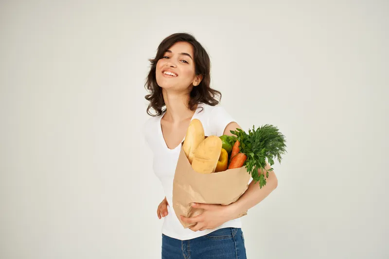 Симпатичная брюнетка с пакетом продуктов из супермаркета для доставки