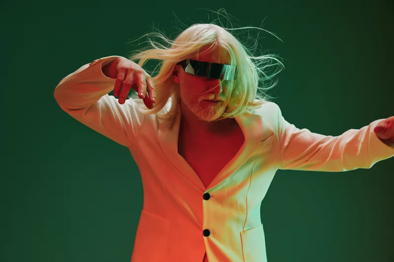 Поразительное изображение футуристического танцора с длинными седыми волосами и гладкими солнцезащитными очками, одетого в современный костюм