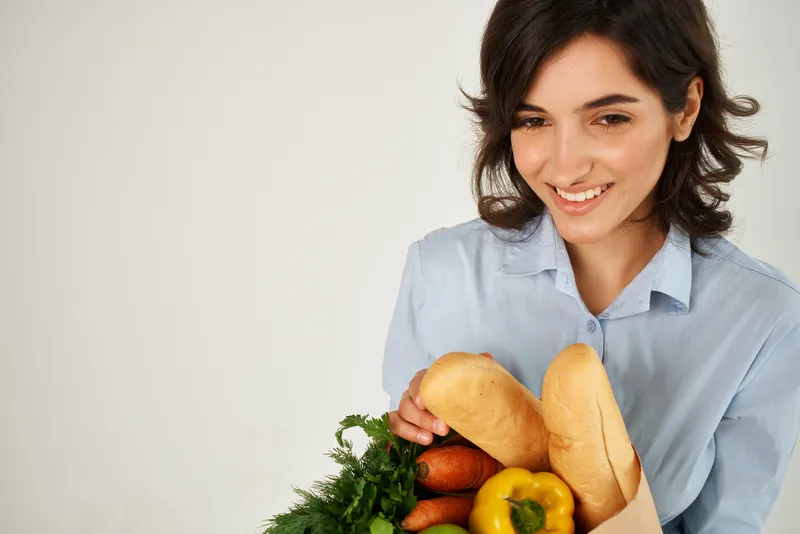 Брюнетка в голубой рубашке с пакетом продуктов, покупки в супермаркете