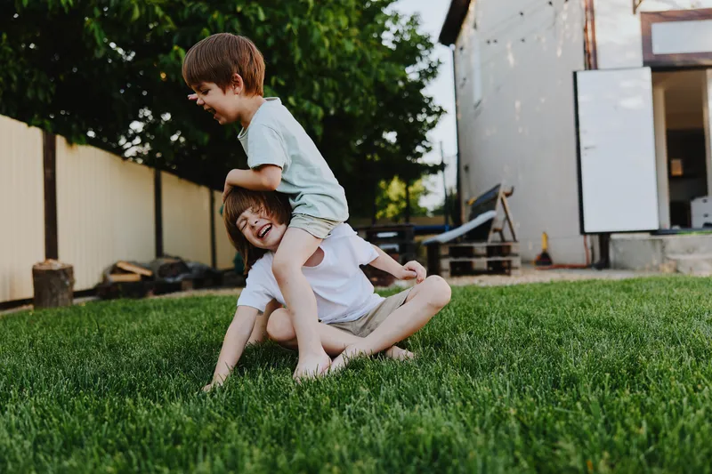 Joyful children playing in the garden, enjoying a sunny day with laughter and fun, surrounded by greenery and a calm atmosphere of summer bliss.