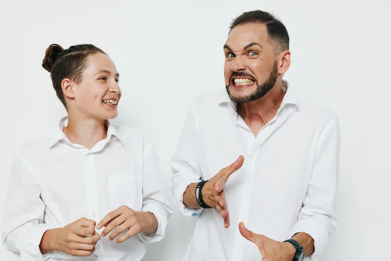 A confident male business professional stands against a solid colored background, exhibiting intense emotion and energetic presence in a striking, studio style moment.