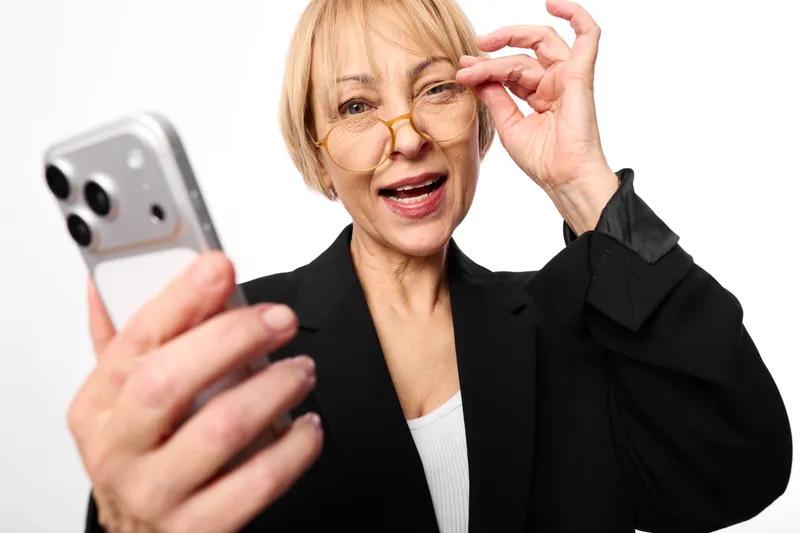 Woman senior glasses smartphone technology communication portrait surprised hand studio, senior woman adjusts glasses while holding smartphone, surprised expression, technology communication concept,