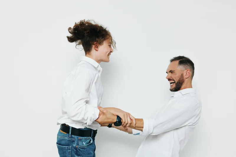 A confident business professional stands with a colleague against an isolated white background, sharing a cheerful moment that conveys friendly energy and strong collaboration.