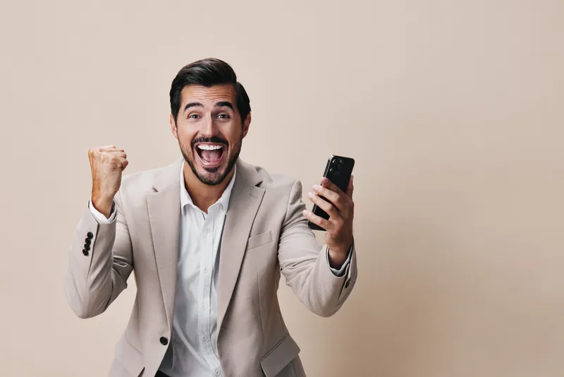 Улыбающийся мужчина в костюме держит смартфон, делая селфи