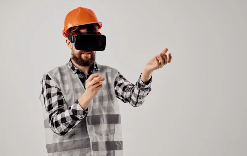 Инженер-строитель в оранжевой каске и 3D-очках на светлом фоне
