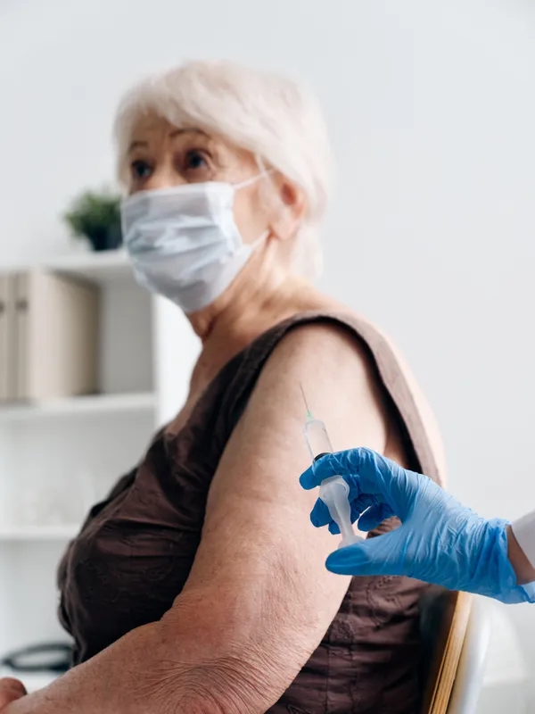 Медсестра со шприцем в руке делает инъекцию в вакцинный паспорт пациента