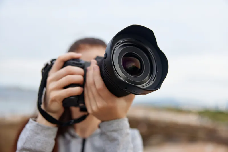 A young woman capturing nature with a professional camera, showcasing her passion for photography The image reflects creativity and focus in a serene outdoor setting