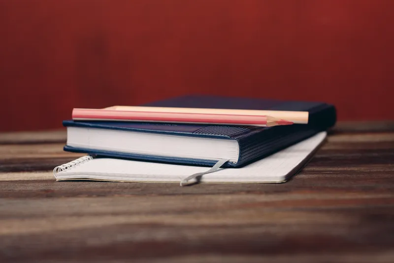 Книги, блокноты, ручки на деревянном столе