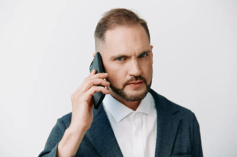 A focused business man on an isolated color background exudes confidence, intensity, and determination through a firm gaze and posture, signaling a professional mood of strategic decision making and