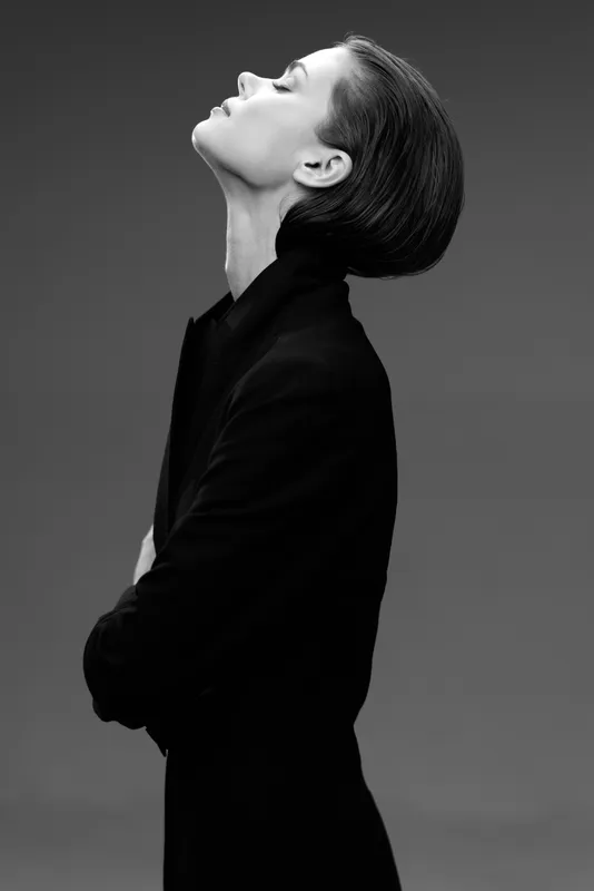 Black and white profile of a woman wearing a black coat with eyes closed in serene expression.