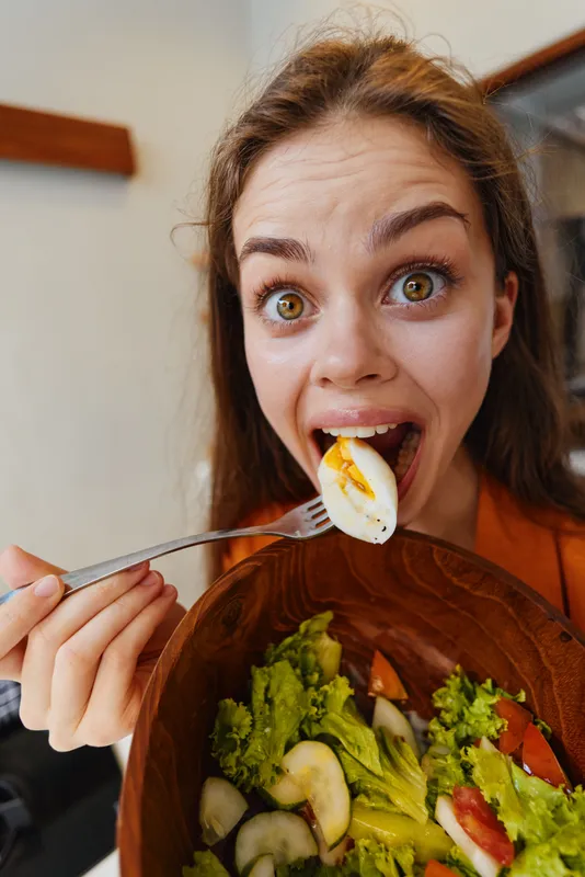 Энергичная молодая женщина, готовая насладиться вкусным салатом со свежими овощами и яйцами, воплощает радостный подход к здоровому питанию