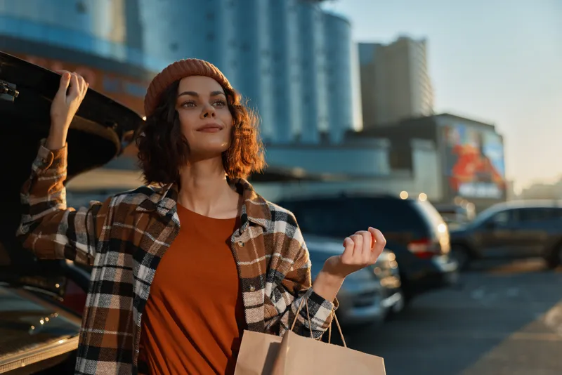 Woman shopping portrait in urban street at golden hour, candid authenticity and lifestyle moment with shopping bags, mindful living and emotional storytelling in warm sunset glow.