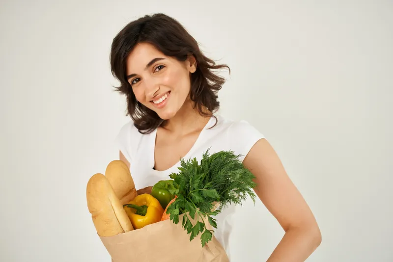 Весёлая брюнетка с пакетом продуктов
