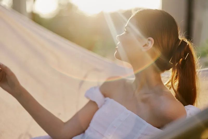 Relaxed woman enjoying sunlight in a hammock, embodying serenity and tranquility in a beautiful outdoor setting Natural light and soft colors enhance the peaceful atmosphere