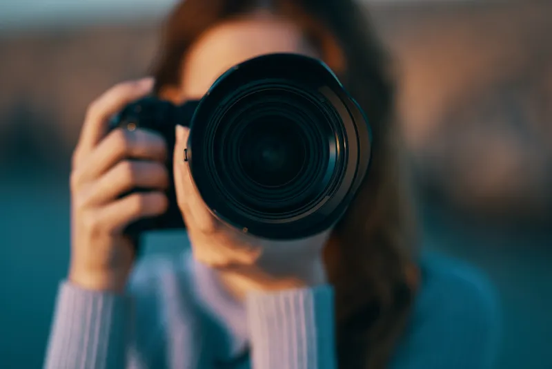 Портрет женщины-фотографа с профессиональной камерой на открытом воздухе, в горах