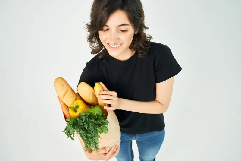 Симпатичная женщина с пакетом продуктов, овощей и полезной еды для доставки