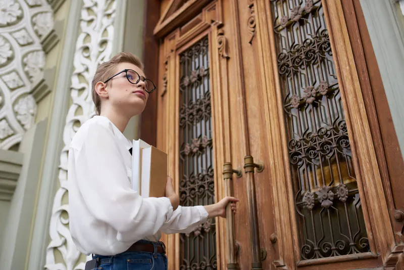 Студент с книгой в руках на открытом воздухе, читает и учится