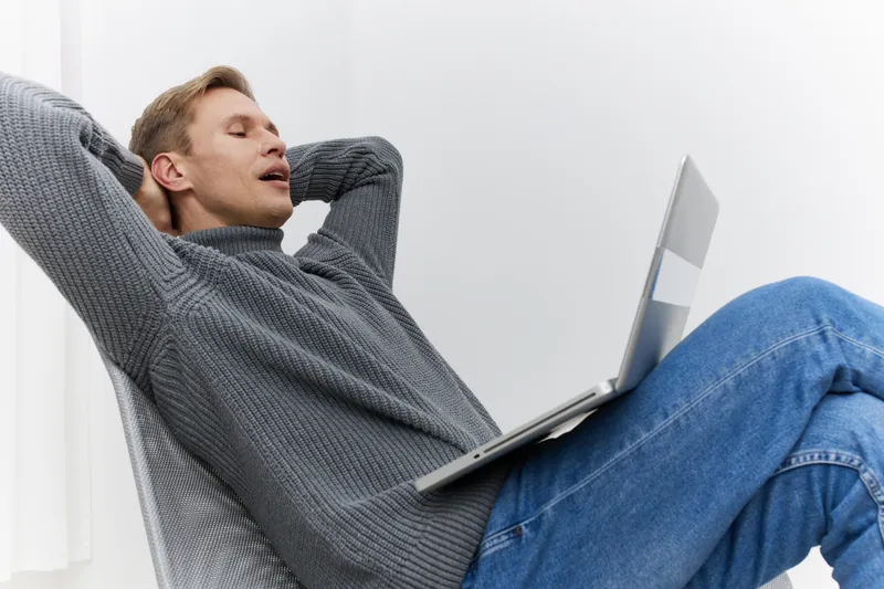 relaxed man working laptop casual sweater jeans sitting chair home digital nomad remote work concept