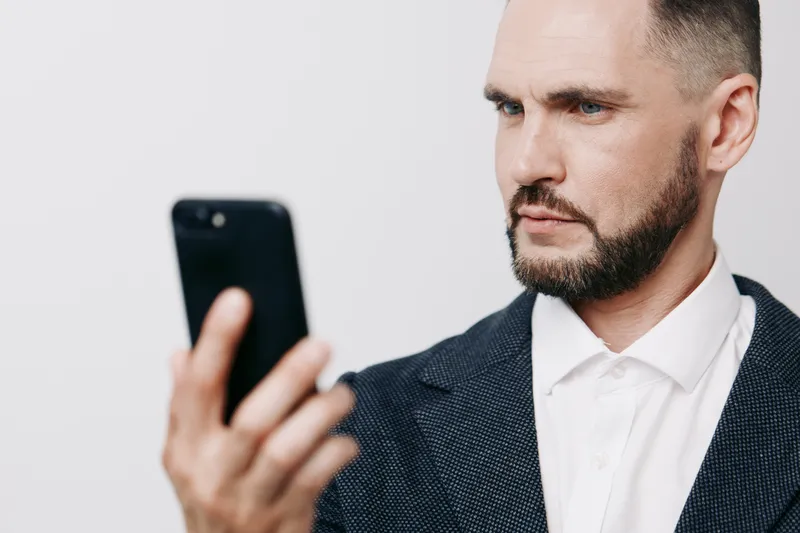 A focused business professional man checks his smartphone, signaling confidence, concentration, and modern focus against an isolated colored background with crisp lighting.