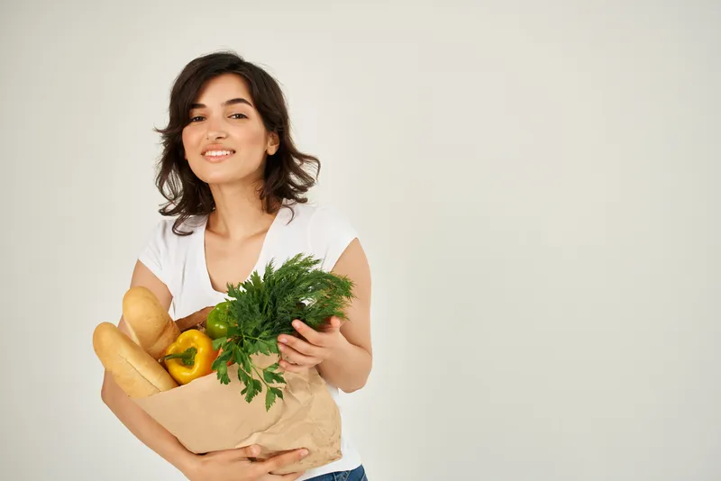Женщина в белой футболке с продуктами здорового питания из супермаркета