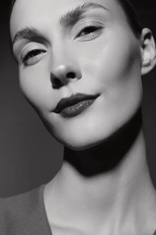 Close-up portrait of a fair-skinned Caucasian woman with smooth skin and natural makeup, showing calm and confidence in black and white.