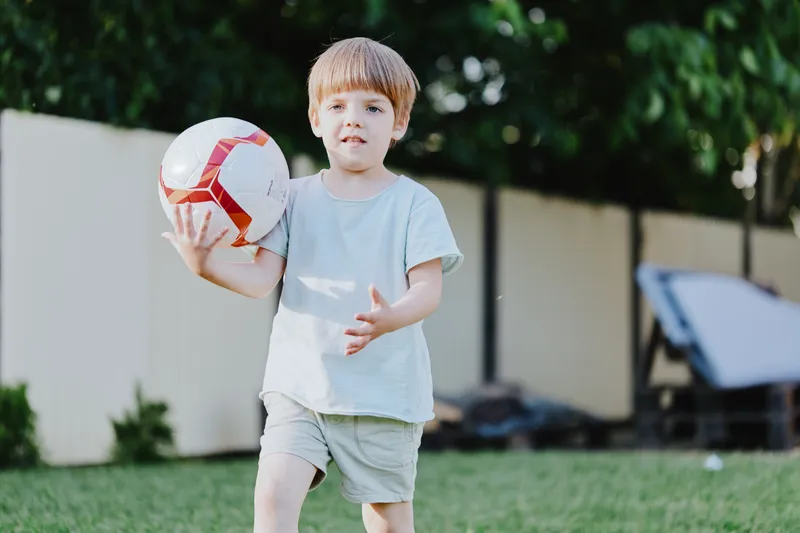 Active boy with soccer ball enjoying outdoor play in the garden, capturing the essence of childhood joy and vitality in natural surroundings.