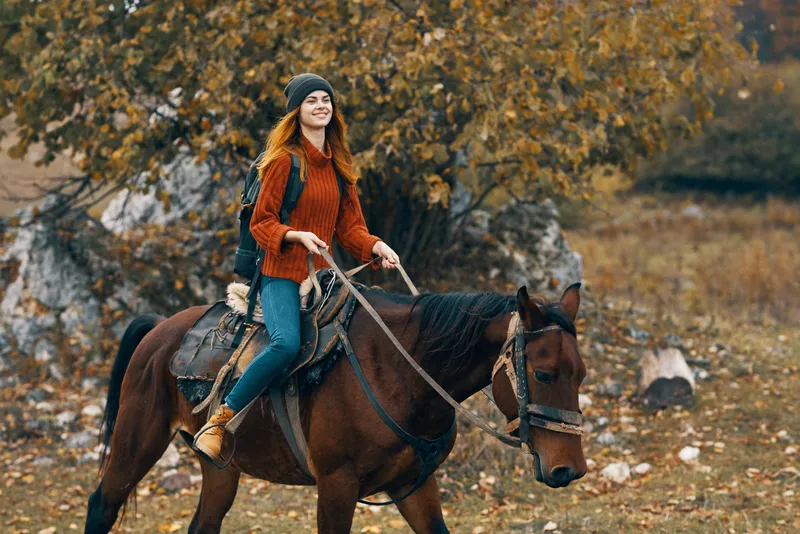 Женщина-туристка верхом на лошади в горах