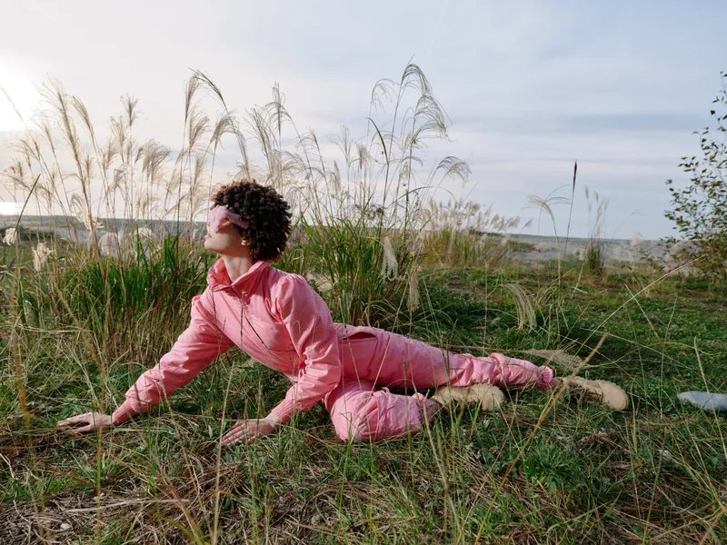 Yoga, fitness, outdoor, nature, woman, stretching in a grassy field, she holds a graceful pose on soft grass, wearing pink, under a clear sky, calm focus and balance in an outdoor routine