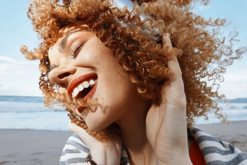 Летнее блаженство: улыбающаяся женщина наслаждается свободой и счастьем на прекрасном пляже