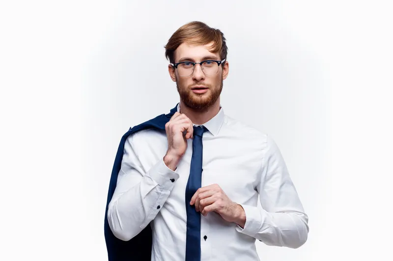 Симпатичный бизнесмен в очках, с пиджаком на плече, в рубашке и галстуке