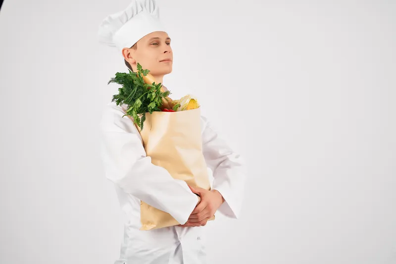 Весёлый повар-мужчина с упаковкой продуктов здорового питания, предоставляющий кухонные услуги