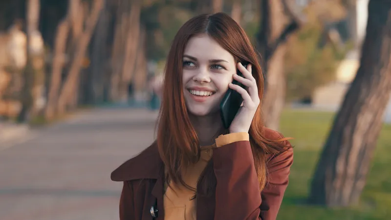 Женщина на открытом воздухе в парке разговаривает по телефону во время прогулки