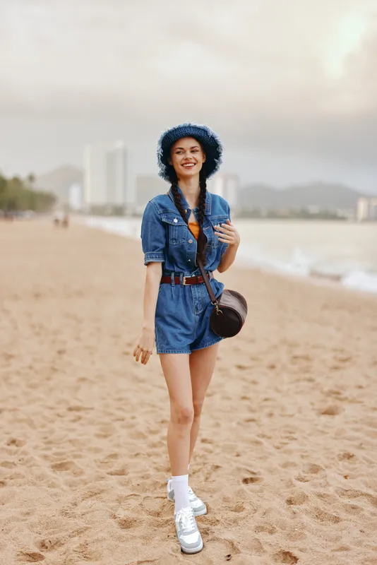 Красота пляжа: счастливая молодая женщина идёт по песку, наслаждаясь летним отдыхом в тропическом раю под голубым небом