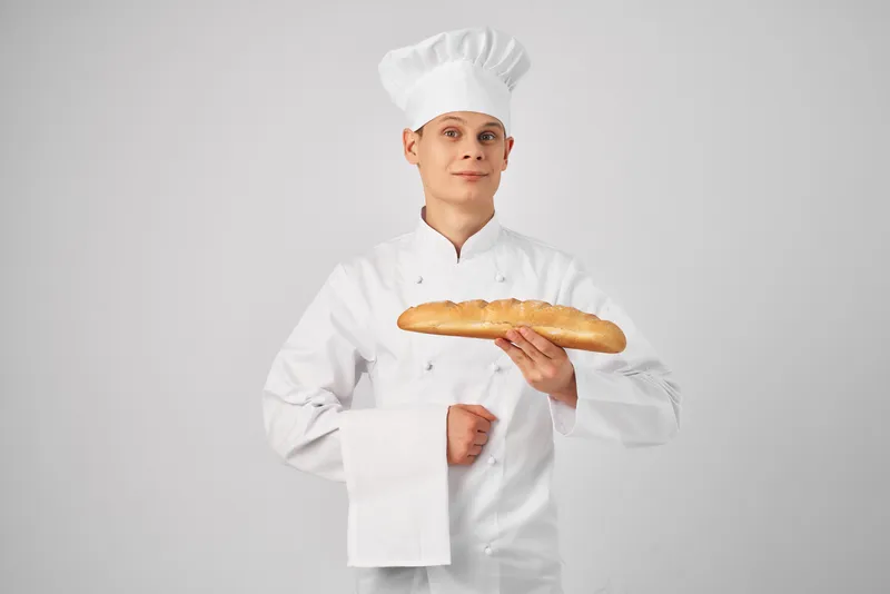 Повар-мужчина держит в руках багет, свежий продукт, профессиональная работа