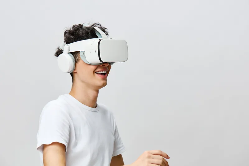 Счастливый молодой человек наслаждается опытом виртуальной реальности в VR-гарнитуре и наушниках