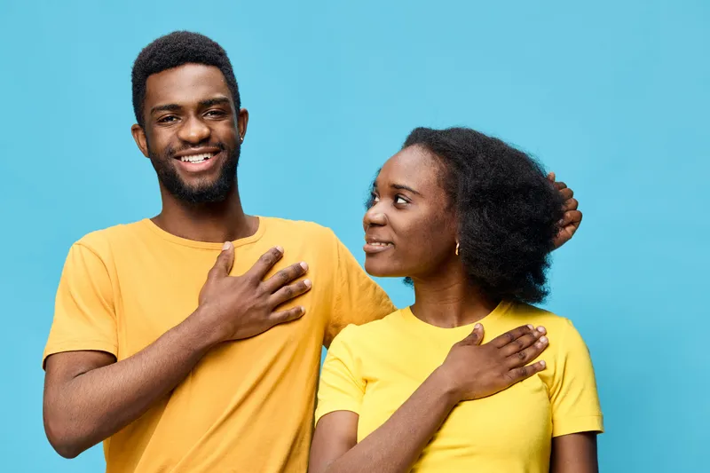 Happy Black couple in yellow t shirts expressing love and connection against a bright blue background, perfect for themes of relationships and positivity