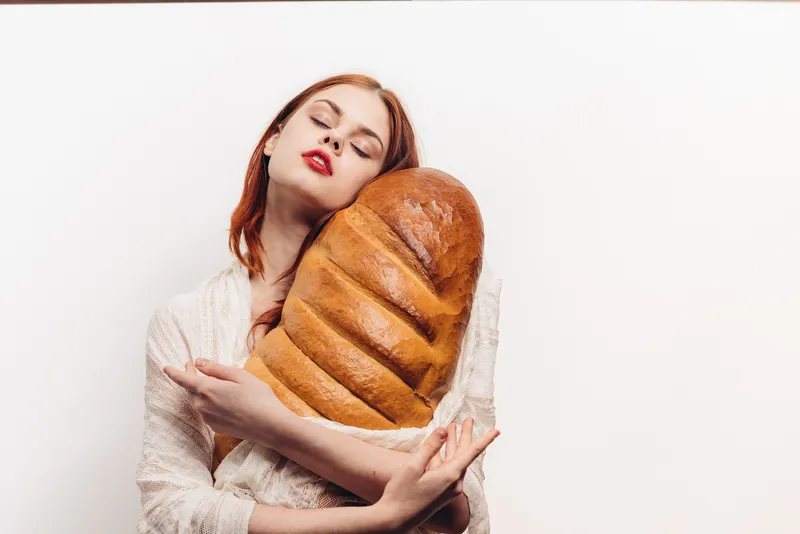 Красивая женщина обнимает батон руками, макияж, на плечах прозрачная ткань