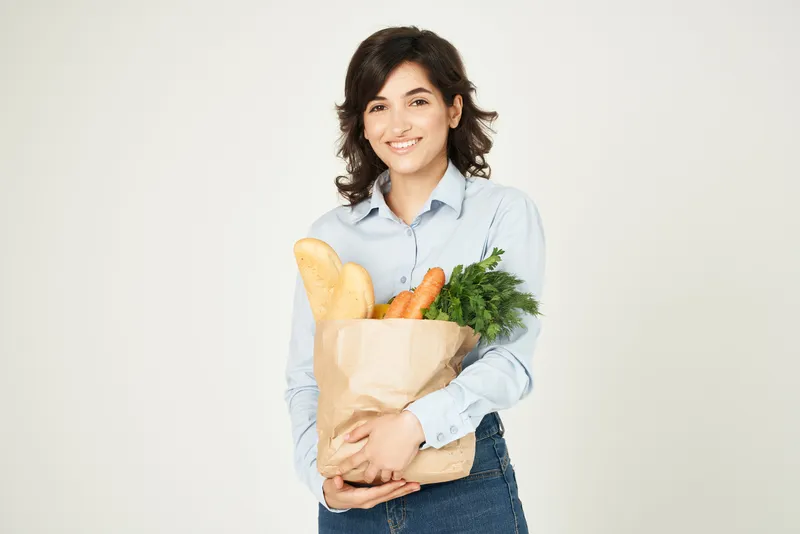 Женщина с пакетом продуктов, домохозяйка, совершающая покупки в супермаркете