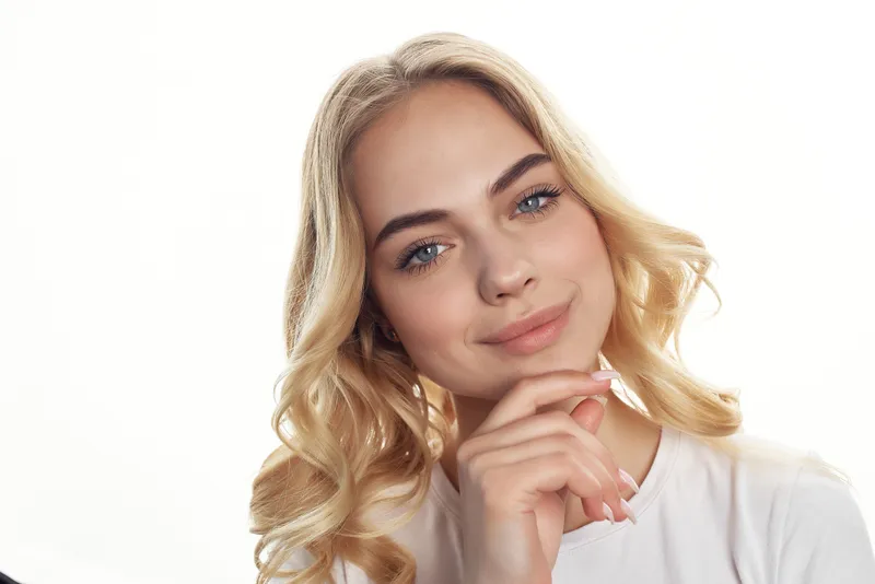 Симпатичная блондинка держит косметику для волос, крупный план лица