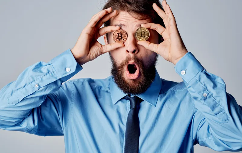 Бизнесмен рядом с криптовалютой Bitcoin на лице, эмоции, финансы, технологии
