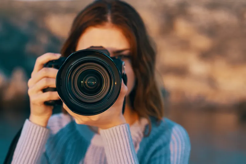 Женщина с профессиональным фотоаппаратом на открытом воздухе в горах, вид спереди