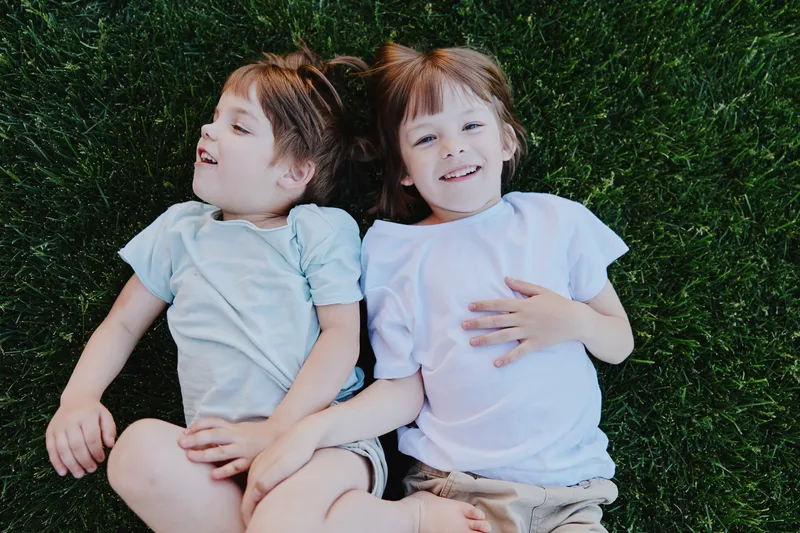 Happy children lying on grass, enjoying a sunny day with joyful expressions and playful poses, perfect for capturing the essence of childhood joy.