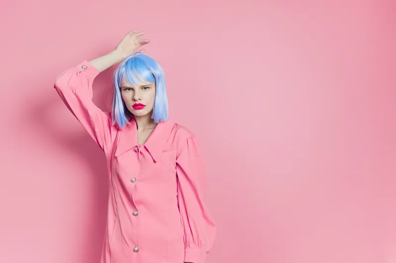 Девушка в синем парике и розовом платье с ярко-красной помадой на изолированном фоне