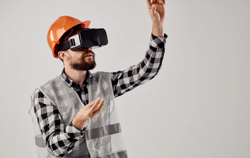 Инженер-строитель в оранжевой каске и 3D-очках на светлом фоне