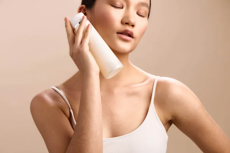 asian woman speaks softly on a white phone against a neutral backdrop, conveying calm communication and focus. her poised posture and serene expression create a modern lifestyle moment.