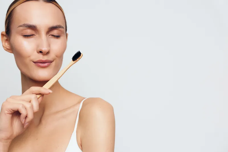 Woman applying makeup with a cosmetic brush, close up portrait for beauty skincare routine, calm expression, grooming concept, minimal white background today