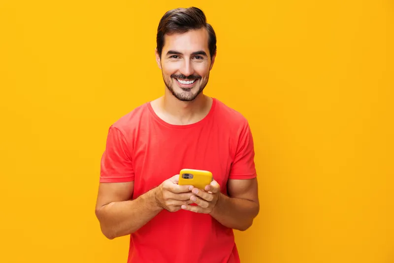 Мужчина общается, держит смартфон, улыбается