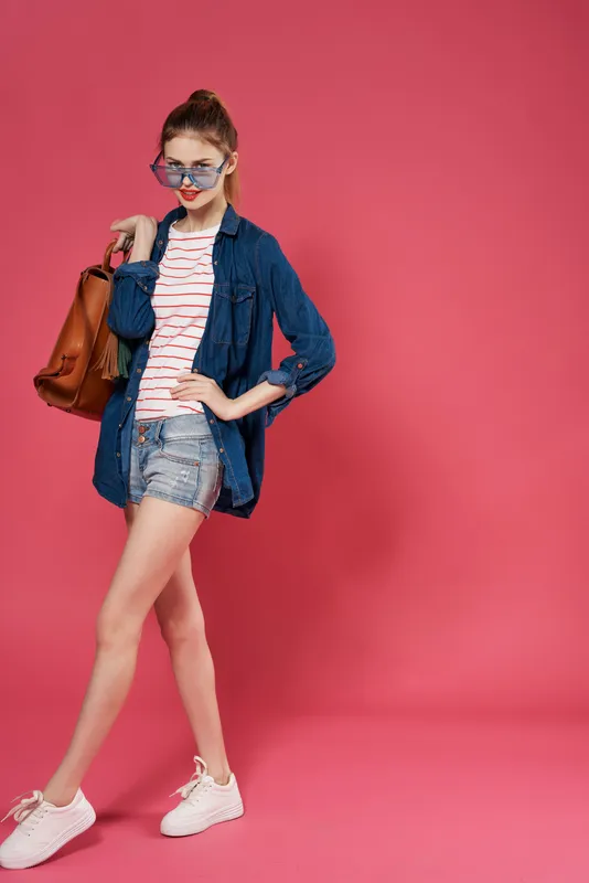 Весёлая девушка с рюкзаком держится за волосы
